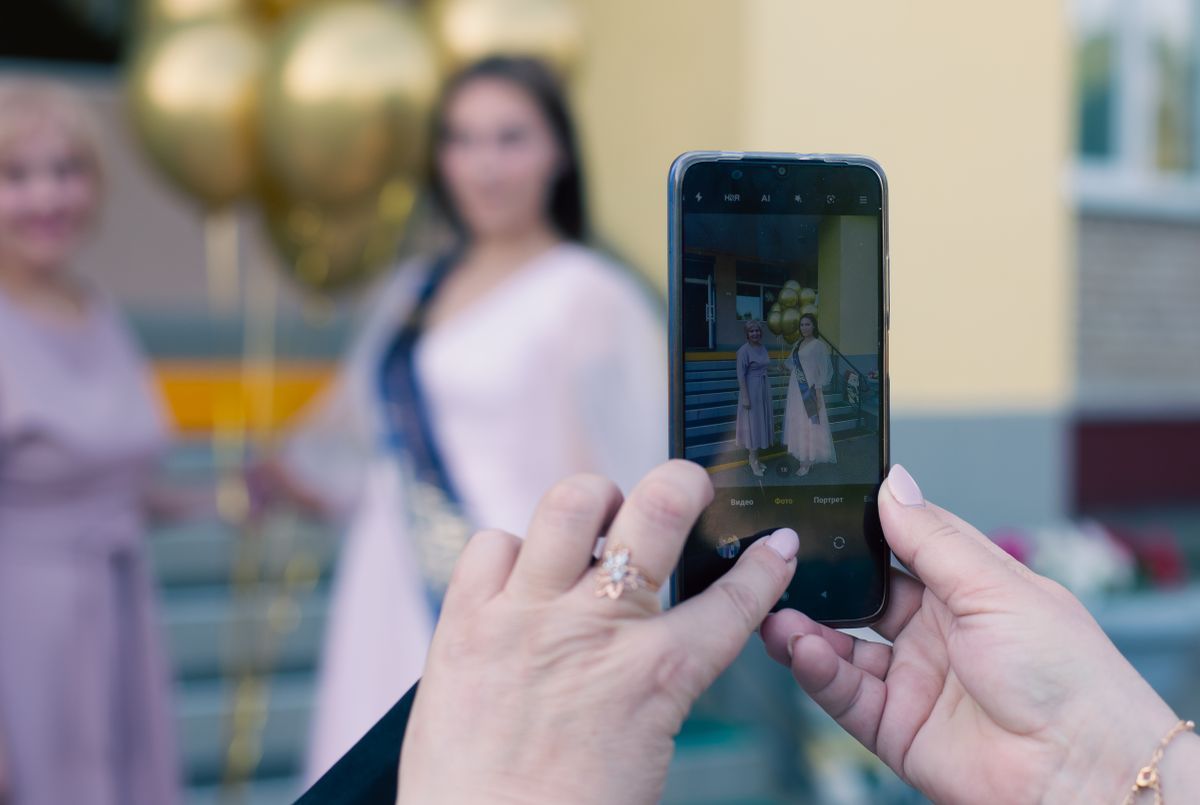 Balonlu iki kadının fotoğrafını telefonla çeken el